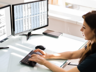 A woman working on a computer with two monitors in front of her.