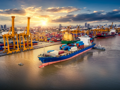 A large container ship docked in a harbor at sunset.