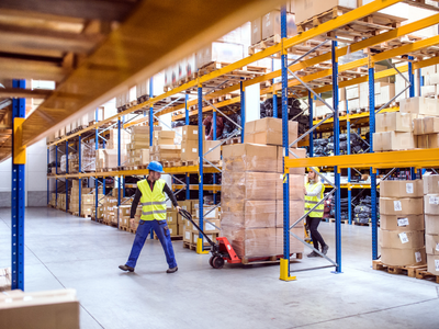 Two people working in a warehouse with pallets.