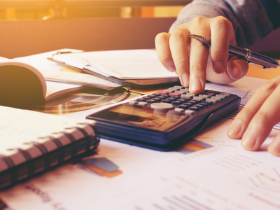 A person is using a calculator at a desk.