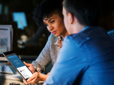 Two people looking at a tablet at a desk.