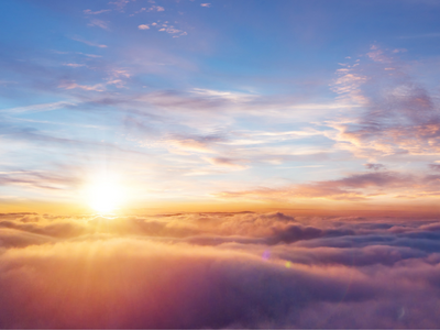 Image of the sun taken above a thick cloud layer, with smaller clouds slightly covering up a blue sky