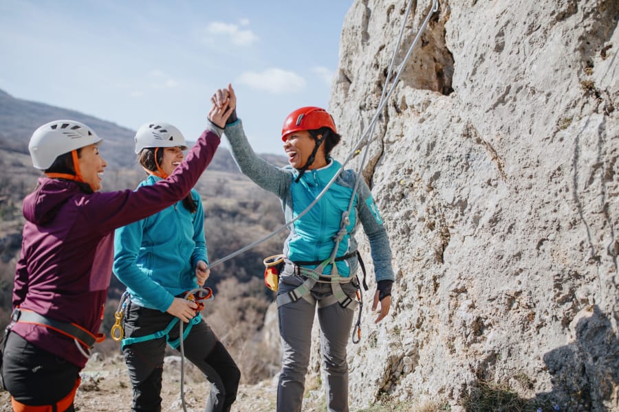 Three people high-fiving each other on a rock.