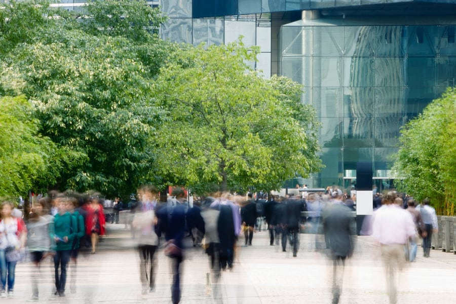 A blurry image of people walking in a city.