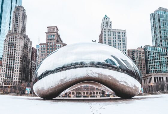 The Cloud Gate sculpture in Chicago on a snowy morning, The Chicago skyline rising behind it.