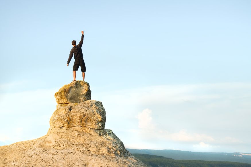 A man standing on top of a mountain with his arms raised.