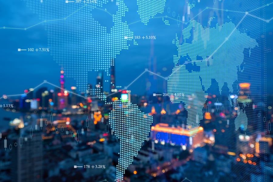 A world map created using an arrangement of dots, two line graphs and some data points, all in front of a cityscape at dusk.
