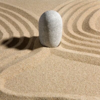 A stone sits in the sand in a zen garden.
