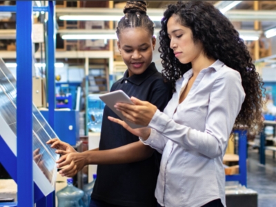 Two women in a factory looking at a tablet.