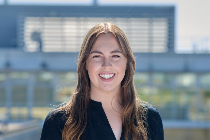 A smiling woman with a blurred building background