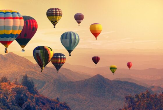 SunSystems Fixed Assets Training image. A group of hot air balloons flying over a mountain.