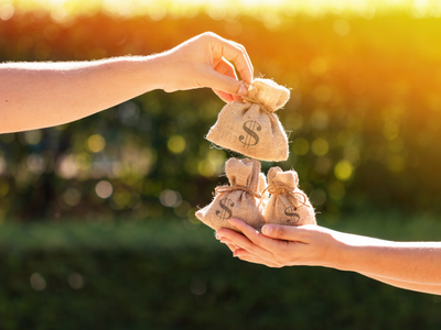 Two hands giving money bags to each other.