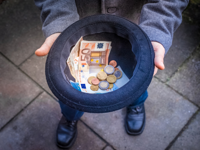 A man holding a hat with money in it.