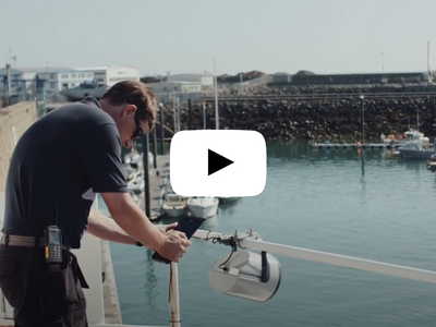 A man is working on a dock with boats in the background.