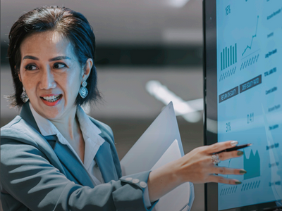 A business woman pointing at a screen with graphs on it.