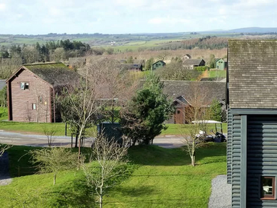 A view from the top of a building overlooking a green field and houses.