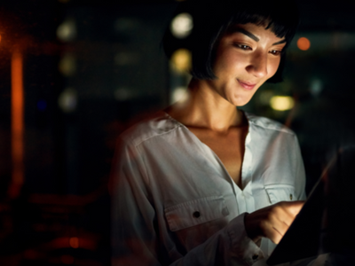 A woman looking at a tablet at night.