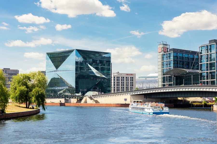 A boat is traveling down a river in front of buildings.