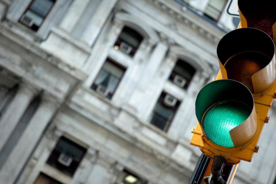 A traffic light with a green light in front of a building.