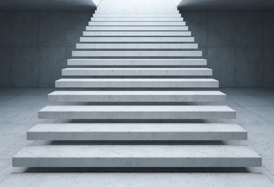 A set of white concrete steps climb up and out of a sunken space, also made from concrete.