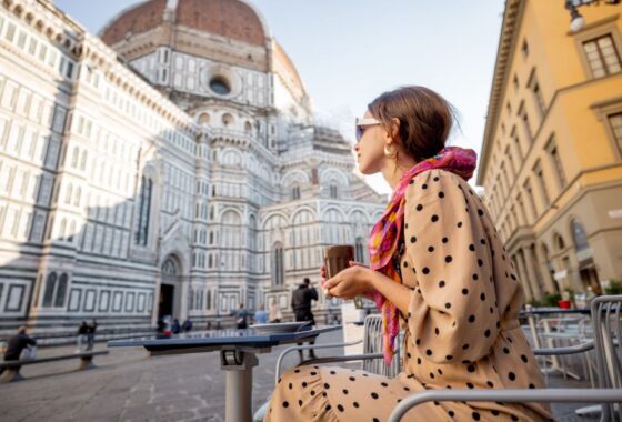 A woman drinking coffee in front of the duomo in florence, italy.
