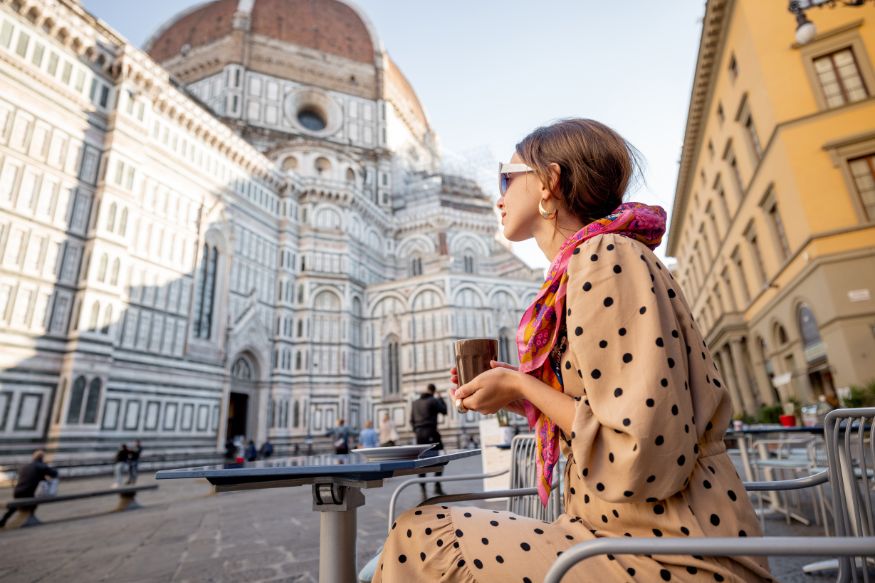 A woman drinking coffee in front of the duomo in florence, italy.