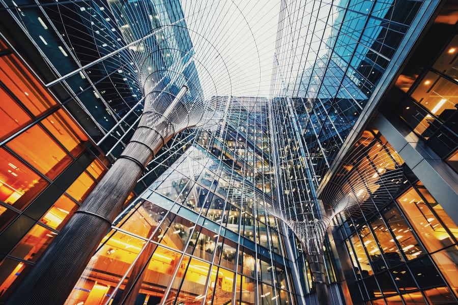 Looking upwards in a courtyard, surrounded by modern glass-fronted buildings and metal tree-like art installations. TouchstoneCloud page image.