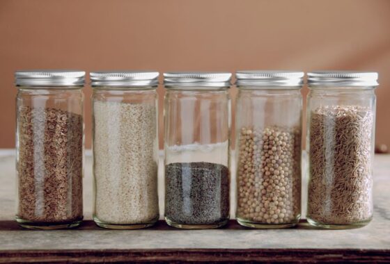 Five glass jars filled with different kinds of grains.