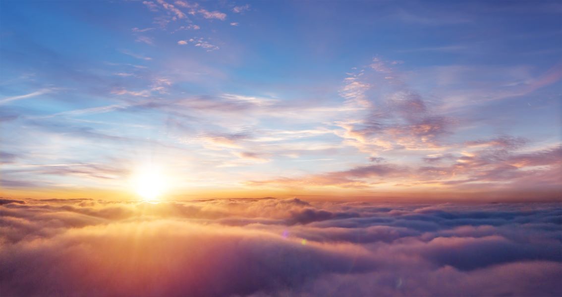 A bright, clear sky seen from above cloud level, the sun seen in the distance slightly to the left of shot.