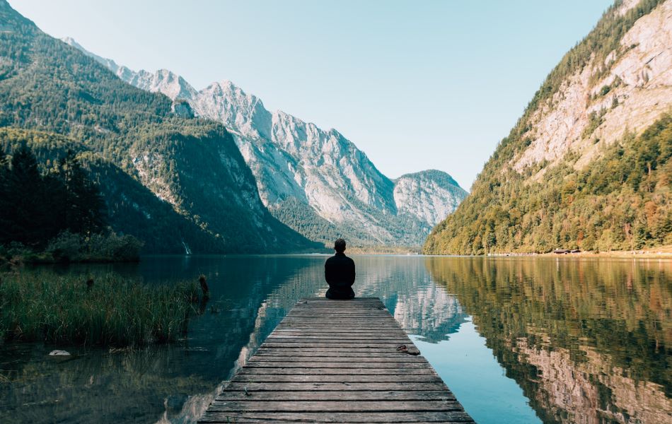 A man sitting on a dock overlooking a lake.