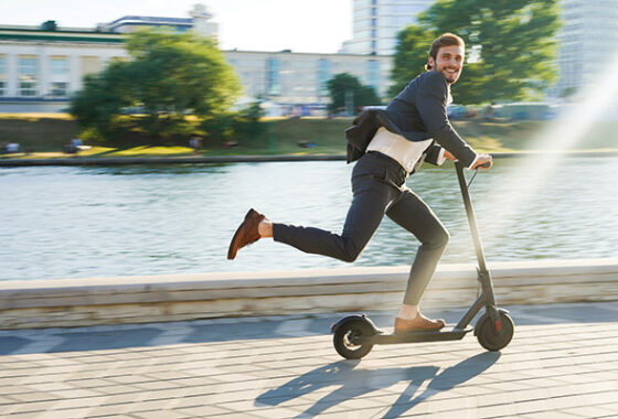 A man in a suit is riding an electric scooter.