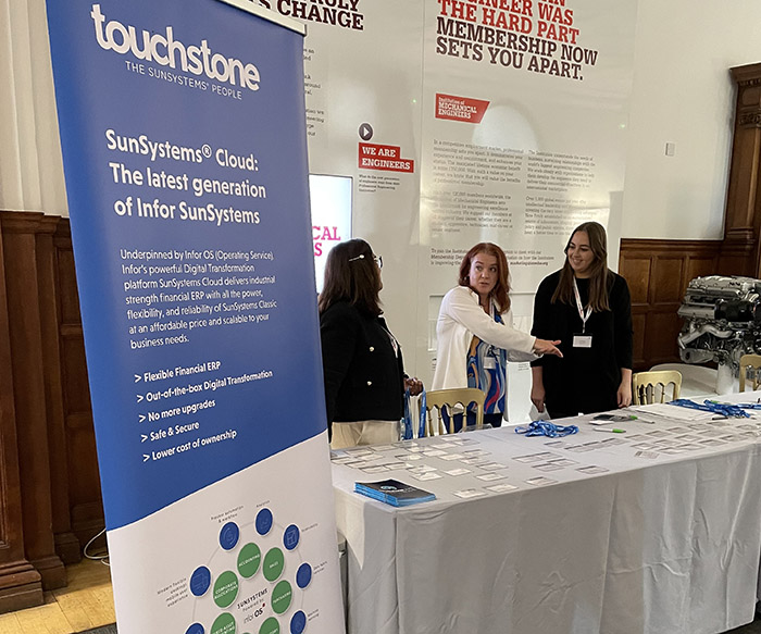 Two women shaking hands in front of a table with a touchstone banner.