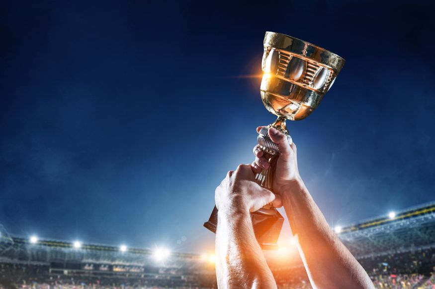 Hands lifting trophy above football stadium