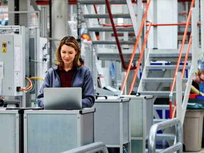 A woman working on a laptop in a factory.