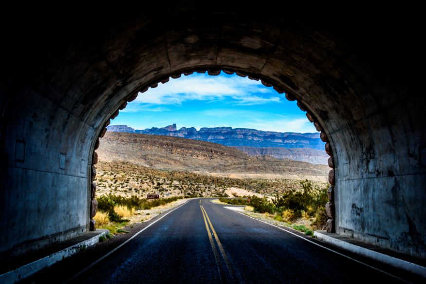 A road through a tunnel with mountains in the background.