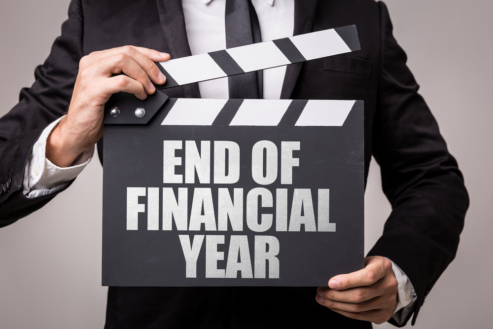 A businessman holding a sign that says end of financial year.