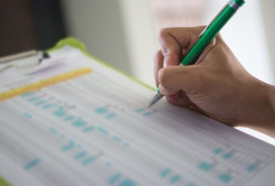 A person writing on a clipboard with a pen.