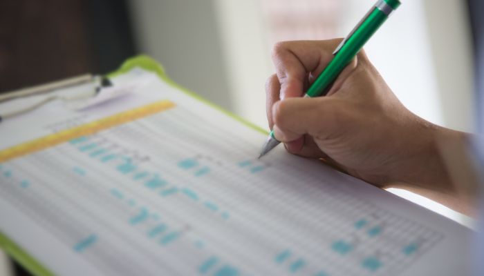 A person writing on a clipboard with a pen.